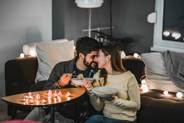 Young couple celebrating Valentine's Day indoors Young couple is in having a romantic dinner at home date night romance stock pictures, royalty-free photos & images