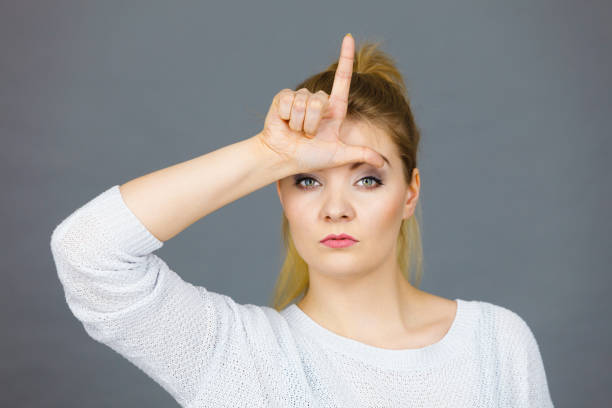 istock Woman showing loser gesture with L on forehead 1192946573