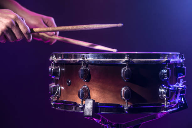 o baterista toca bateria. fundo azul e vermelho bonito, com raios de luz. belos efeitos especiais fumaça e iluminação. processo de tocar um instrumento musical. foto de close-up. - caixa clara - fotografias e filmes do acervo