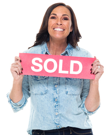 Front view / one person / waist up / portrait of adult beautiful brown hair / long hair caucasian female / young women / mid adult women / mid adult standing wearing button down shirt / shirt / pants who is smiling / happy / cheerful / laughing and holding sign / sale
