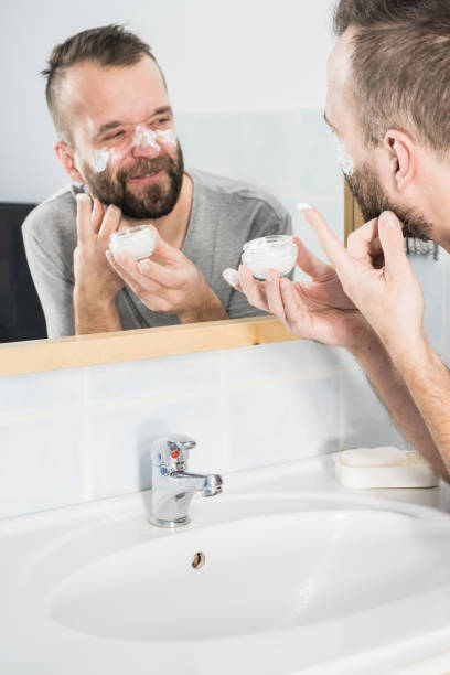 istock Man applying moisturizer cream in bathroom 1192948095