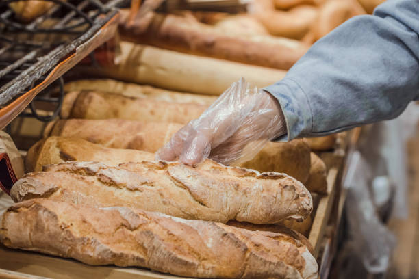 молодая женщина берет с прилавка в супермаркете свежий хлеб. - bread bakery women cake стоковые фото и изображения