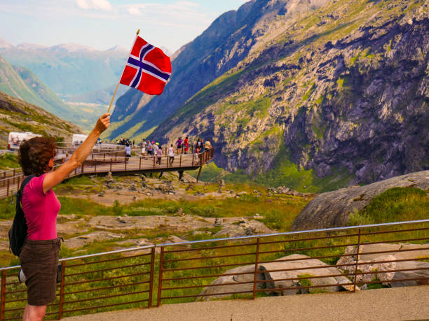 istock Tourist with norwegian flag on Trollstigen viewpoint 1192950481