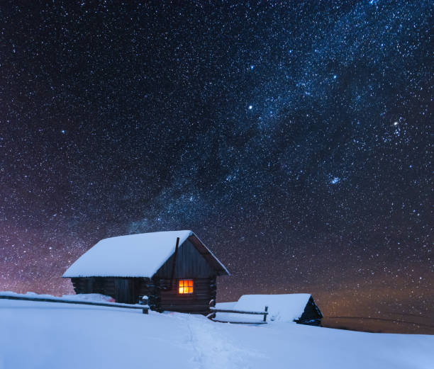 istock Dramatic wintry scene with snowy house with warm light 1192950588