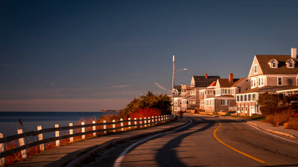 Uphill road with shadows and houses on Cape Cod coastline at Sunrise stock photo