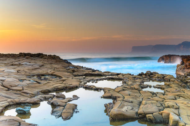 Smoke Haze and Sunrise from Tessellated Rock Platform Capturing the smoke haze sunrise from North Avoca Beach on the Central Coast, NSW, Australia. avoca beach photos stock pictures, royalty-free photos & images