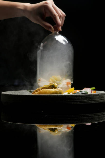 Minute smoked butterfish escalope served with steamed vegetable.  Exquisite dish. Creative restaurant meal on black with reflection
