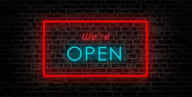 Photo of we are open sign. neon illuminated blue and red font on brick wall.