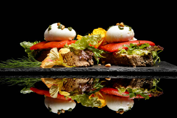 istock Open faced sandwich, Toasted cereal bread with grilled pepper and poached egg on a bed of lettuce. Food photography on black with reflection. 1192977566