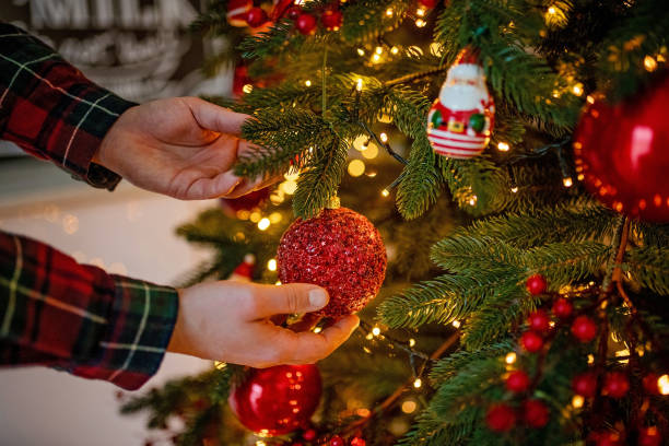 istock man decorates a festive Christmas tree with balls. Happy New Year 1192979227
