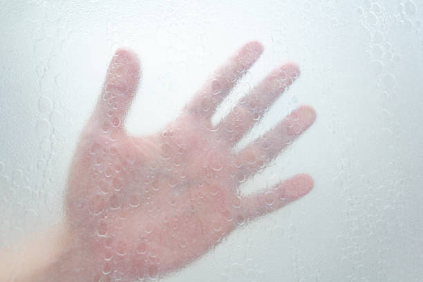 istock hand through a shower screen with drops on a light background 1192982181