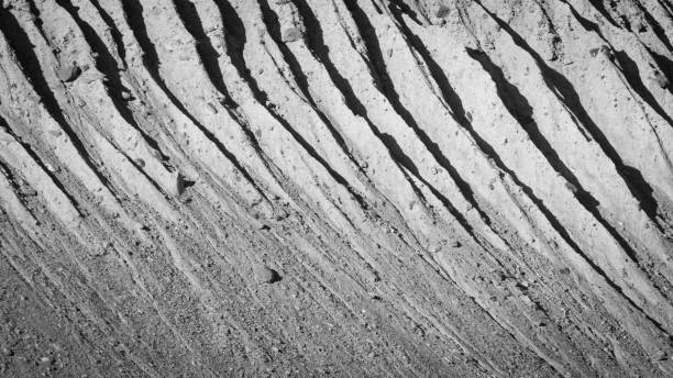 Light and shadow paint abstract patterns on ridges and gullies of a side moraine wall. stock photo