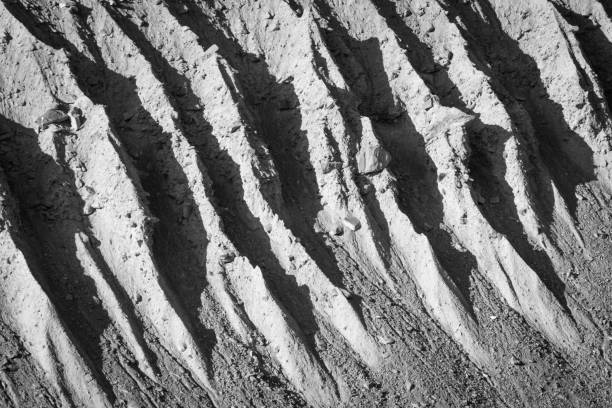 Light and shadow paint abstract patterns on ridges and gullies of a side moraine wall. stock photo