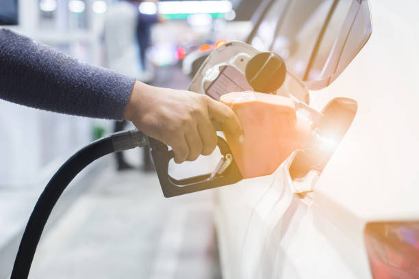 fermez-vous vers le haut de la poignée d'homme pompant la buse de carburant d'essence dans le réservoir pour la voiture à la station-service. - oil pump flash photos et images de collection