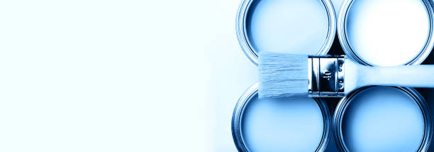 Four open cans of paint with brushes on bright background.