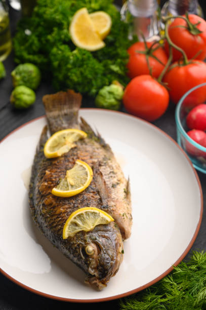 istock Tasty fish cooked with lemons on a background of fresh vegetables.Vertical frame 1192999416
