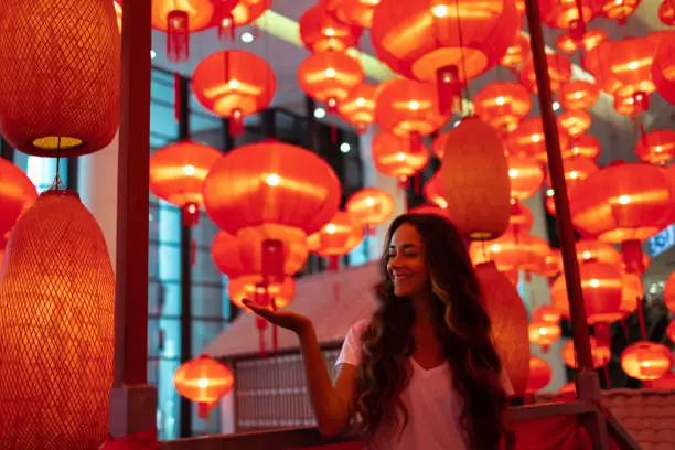 Photo of Happy tourist woman enjoying traditional red lanterns decorated for Chinese new year Chunjie. Cultural asian festival in Beijing.