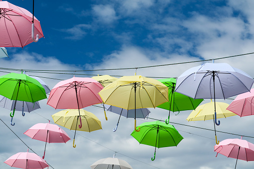 colorful umbrella line wire moving by wind on blue sky white cloud background