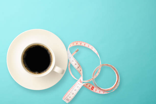 una taza de café con cinta métrica sobre fondo azul claro - caffeine full frame studio shot horizontal fotografías e imágenes de stock