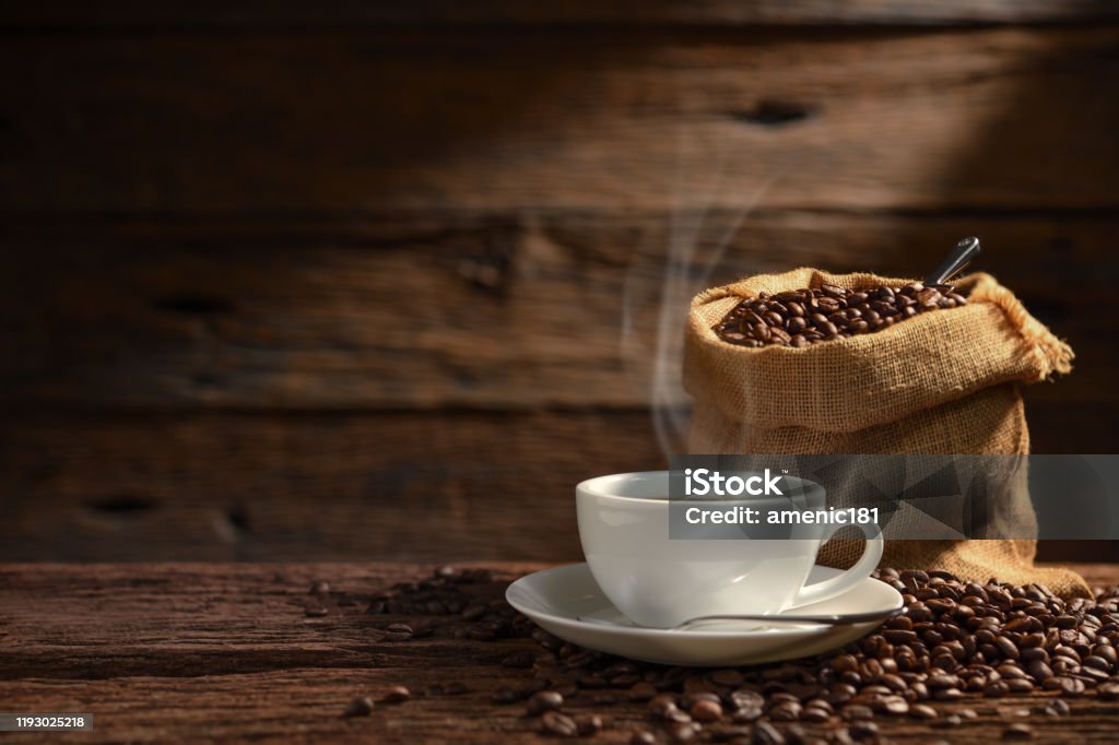 Cup of coffee with smoke and coffee beans on old wooden background Coffee - Drink Stock Photo