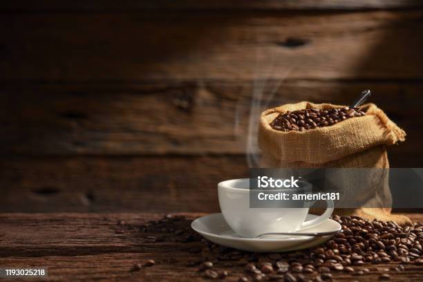 Cup Of Coffee With Smoke And Coffee Beans On Old Wooden Background Stock Photo - Download Image Now