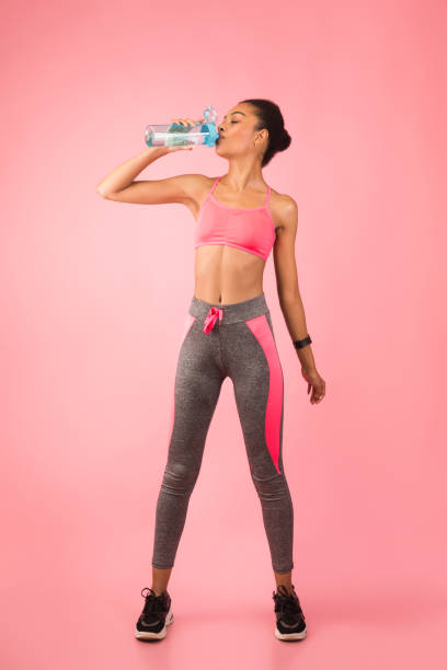 fitness lady drinking water from bottle, studio shot, full length - aerobics beautiful bottle body fotografías e imágenes de stock