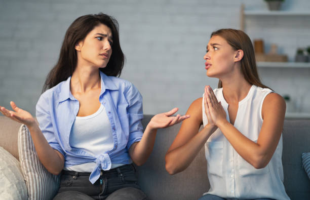 Girl Refusing To Do Favor For Friend Sitting On Sofa Bad Friendship. Girl Refusing To Do A Favor For Begging Friend Sitting On Sofa At Home. Selective Focus doing a favor stock pictures, royalty-free photos & images