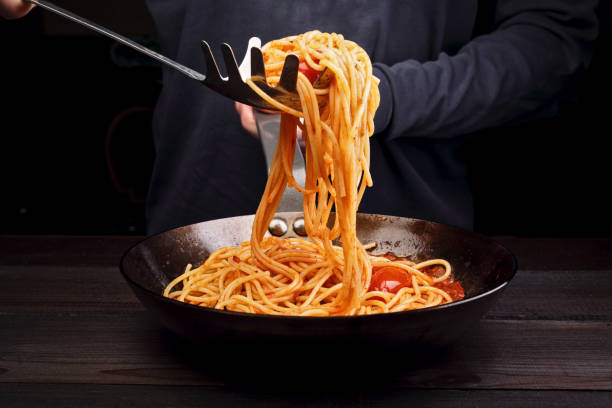 istock A man is cooking spaghetti pasta with tomatoes and spices. Dark background 1193033992