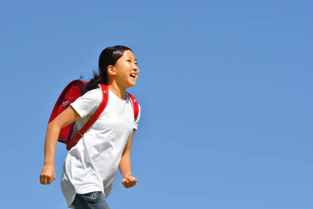 istock Japanese elementary school girl running in the blue sky 1193034304