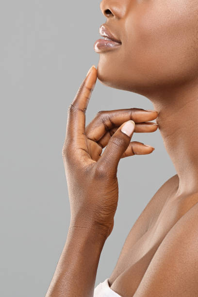 Unrecognizable afro woman touching her chin after plastic surgery Chin augmentation. Unrecognizable afro woman touching implant in her face, happy with result of plastic surgery, gray background with free space chin stock pictures, royalty-free photos & images