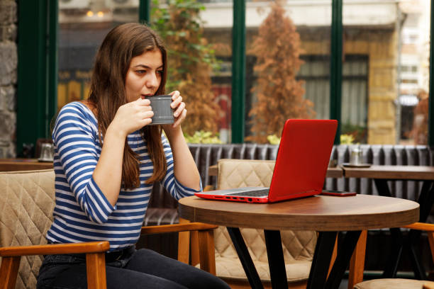 istock Young Woman Drinking Coffee and Using Laptop in a Cafe 1193035622