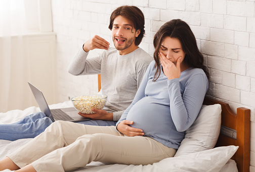 Heightened Sense Of Smell During Pregnancy. Pregnant woman feeling sick because of popcorn that her husband eating at home