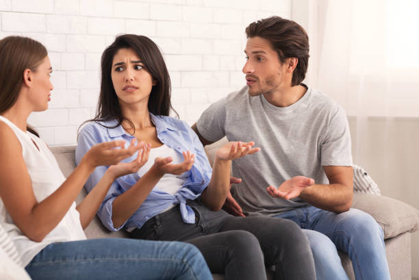 istock Three Friends Having Quarrel Sitting On Sofa At Home 1193035739