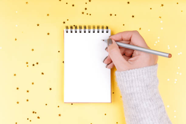 istock White notebook sheet on yellow background with gold sequins 1193039350