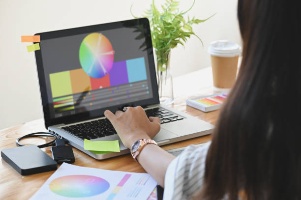 istock Graphic designer her selecting colour with laptop and creative accessories on table. 1193042701