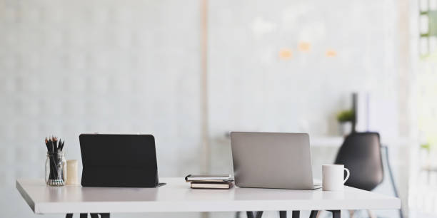 istock Office desk workspace with laptop, tablet and office supplies on white table in modern office. 1193044178