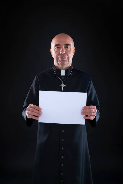 istock Bald priest holding copy space black paper 1193047508