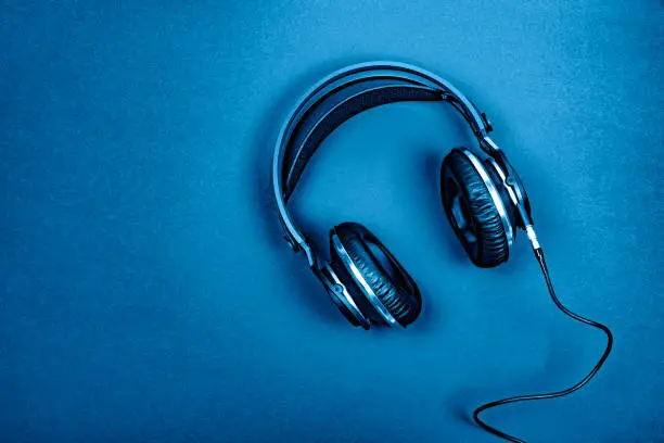 Top view of professional headphones on a  textured  background colored in blue. Copy space.Musical concept. Color of the year 2020.