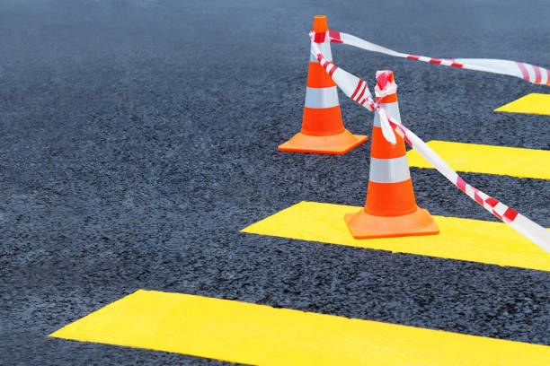 Traffic cones, protective tape on a pedestrian crossing. Red and white ribbon and street cones Traffic cones, protective tape on a pedestrian crossing. Red and white ribbon and street cones central reservation stock pictures, royalty-free photos & images
