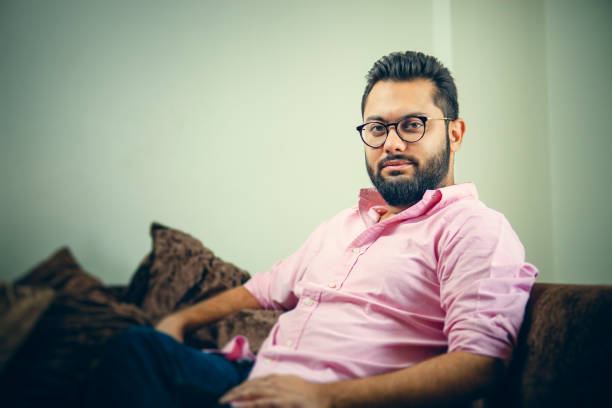 istock Leisurely, confident man sits relaxed on a couch and looks at the camera. 1193053909