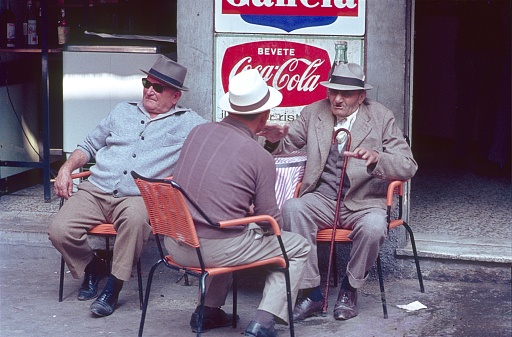 Bologna, Emilia-Romagna, Italy, 1968. Three Italian seniors sitting at a table in front of an ice cream cafe.