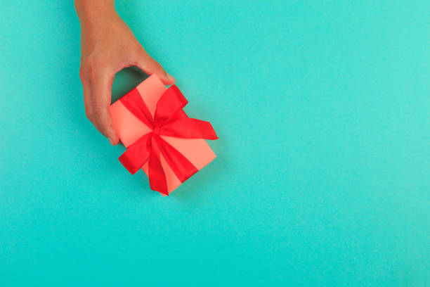 istock gift in female hands on a colored background top view. 1193057219