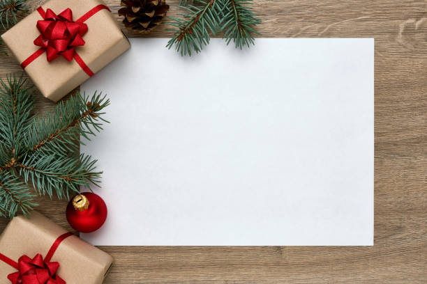christmas or new year composition. white sheet of paper with copy space, gift boxes, christmas ball and christmas tree branches on wooden background. flat lay, top view, horizontal layout - prenda de natal fotos imagens e fotografias de stock