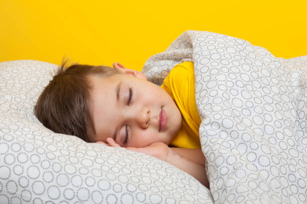 Young boy 5 years old is sleeping at the yellow wall