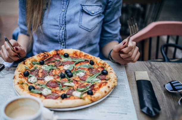 istock Woman eating pizza outdoors in pizzeria 1193063201