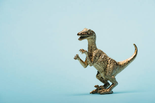 istock Golden toy dinosaur on blue background with copy space 1193064502