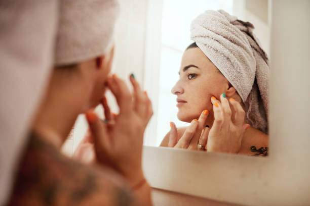 I'll find those zits and I'll zap them Shot of an attractive young woman inspecting her face in the bathroom mirror woman wrapped in bath towel stock pictures, royalty-free photos & images