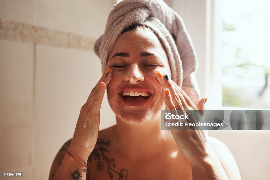 Beauty starts with being good to your skin Shot of a young woman giving herself a facial at home Women Stock Photo