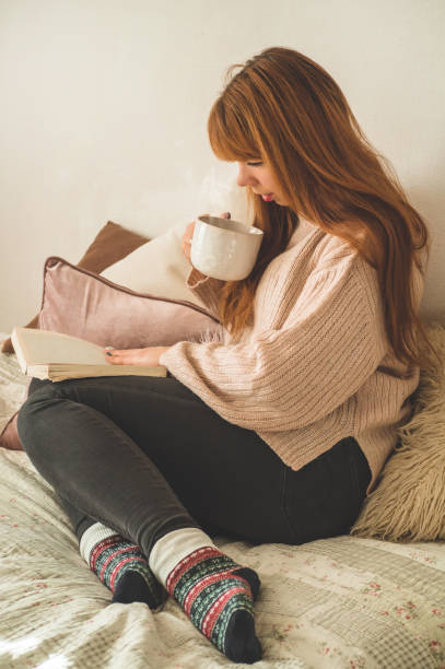 istock Woman drinking hot tea and reading book. Development and relax 1193064866