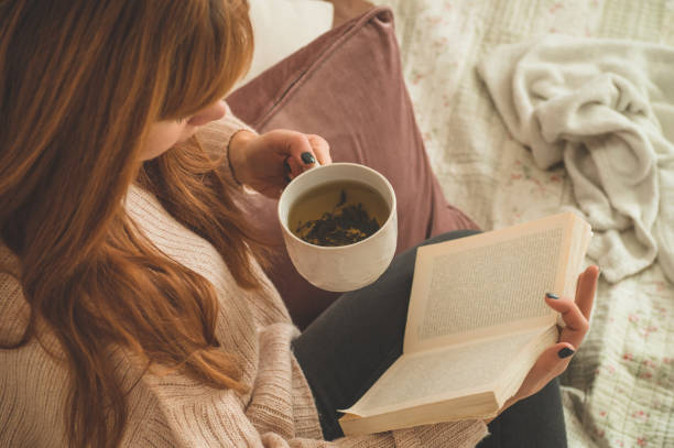 istock Woman drinking hot tea and reading book. Development and relax 1193064956